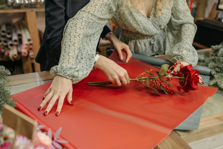 Florist arranging a flower bouquet with red blooms in a shop setting.